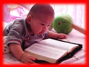 Image of a little bitty baby looking at an open Bible