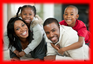 Image of a mother and father with their son and daughter on their back laying facing the camera in the living room